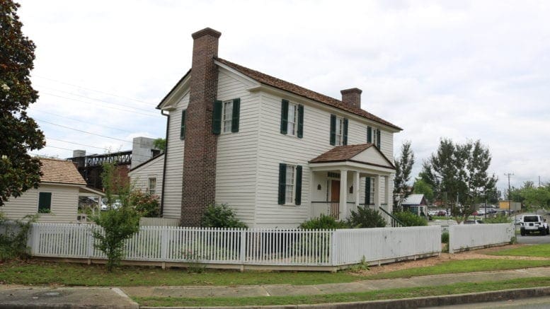 William Root House, a two-story white wooden house with an external chimney surrounded by a picket fence