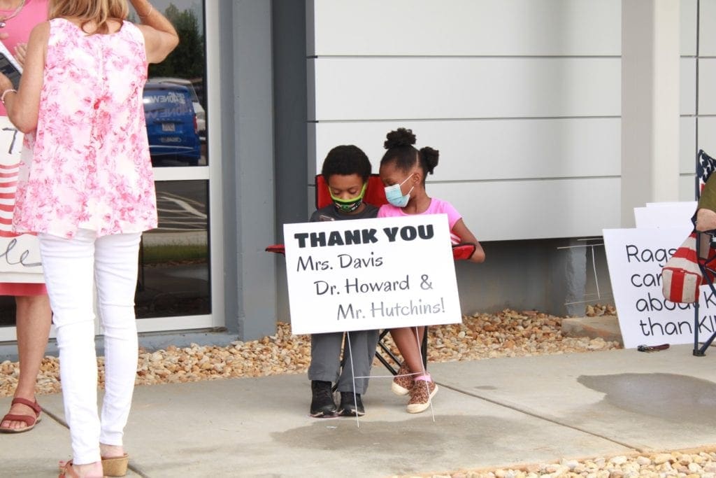 Two children holding sign with thanks to the three Black school board members