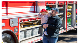 Photo of man holding child by fire truck