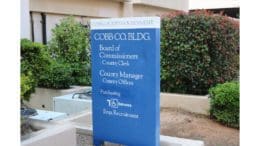 Cobb County government building sign, a vertical rectangular sign with the words "Board of Commissioners," "County Clerk," "County Manager," "County Office," "Employment," and a wheelchair entrance icon