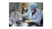 photo of a lab technician wearing a mask working with glass vials