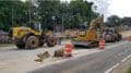 Road construction equipment on shoulder of road with orange safety barriers