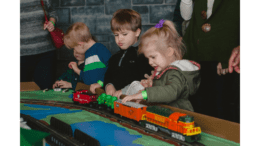 Children playing with a model train set on a platform