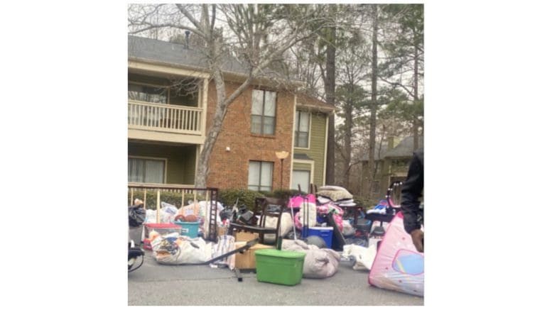 photo of an evicted family's belongings piled up in front of an apartment building