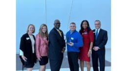 Standing left to right dressed in business attire: 2022 Cobb Chamber Chairwoman Britt Fleck, Cobb Chamber CEO Sharon Mason, Powder Springs Mayor Al Thurman, 2021 Powder Springs Citizen of the Year Kelly Fisk, South Cobb Area Council Director Delphine LaGroon, and South Cobb Area Council Director Smith Peck.