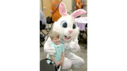 Child sits on lap of huge Easter Bunny