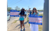 Two women holding up signs opposing Lost Mountain cityhood