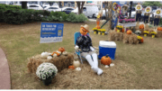 A scarecrow with a pumpkin head in a lawn chair