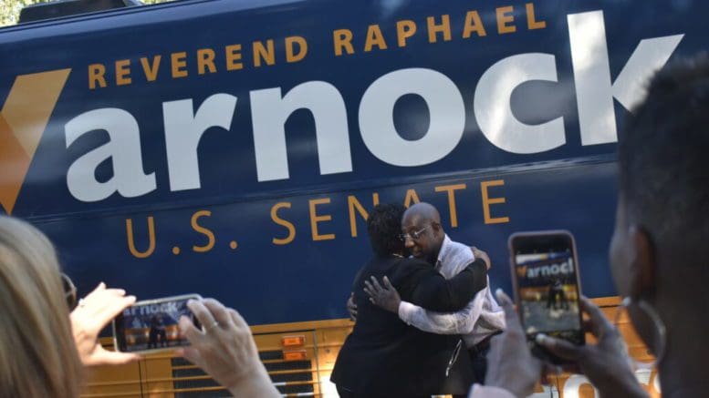 Stacey Abrams and Sen. Raphael Warnock embrace before speaking at a Warnock rally in Marietta. Ross Williams/Georgia Recorder