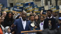 Raphael Warnock at microphone surrounded by supporters