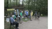 A group of people, one on a bicycle, stand around a table set up on the Silver Comet Trail