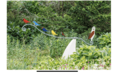 a statue of a row of colorful birds perched on a stylized metal branch
