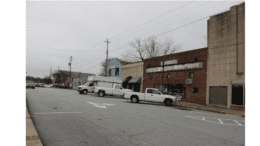 A scene along Broad Street in Austell GA, rows of storefront with diagonally parked cars