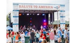 A crowd in front of a live band on a stage marked Kennesaw Salute to America