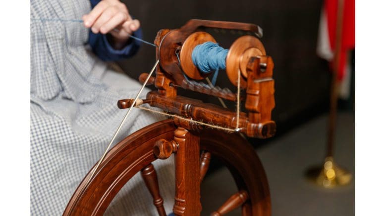 a 19th Century spinning wheel rolling up yarn