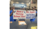 Children hold up sign stating "Have a thriving school year" and "we support National Night Out"