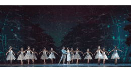 A long row of ballet dancers with a man and woman at the center