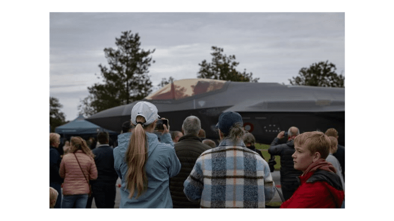 A group of Danish citizens look at an F-35 fighter jet