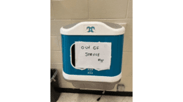 A wall hand sanitizer with an "out of order" sign