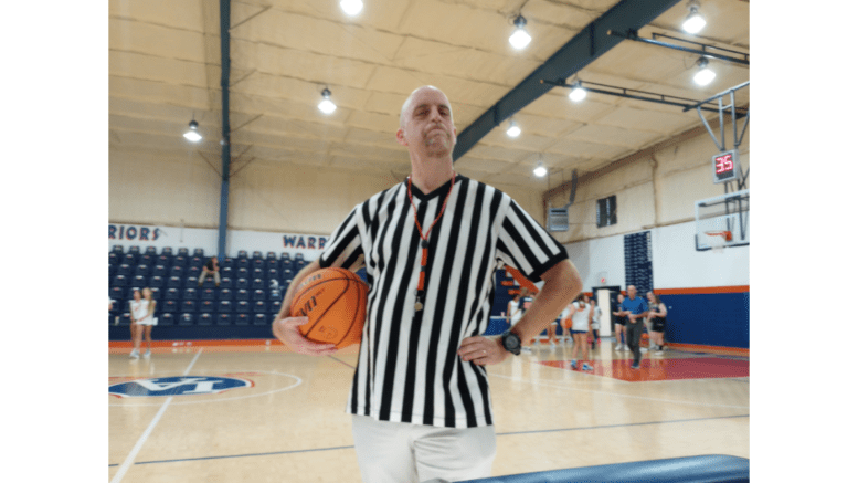 John Tures in a referee uniform holding a basketball