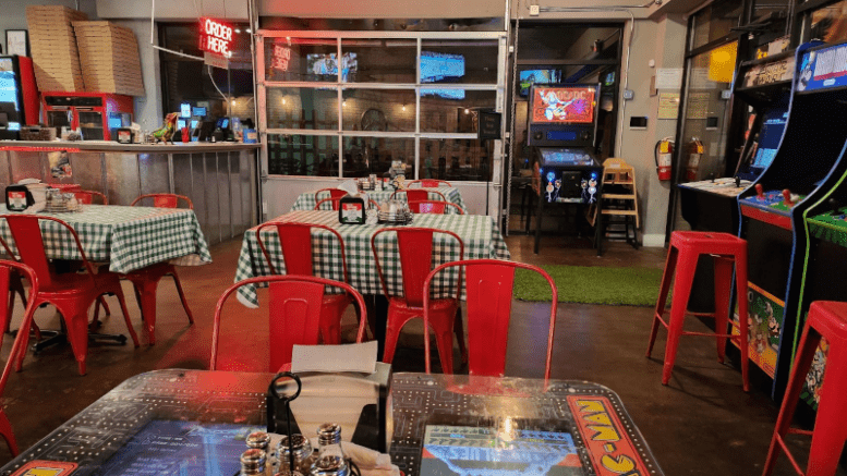 The inside of an arcade restaurant with tables surrounded by retro games