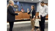 Representative Lisa Campbell swears in new Kennesaw Council member Madelyn Orochena; Orochena's daughter and husband are by her side, all holding hands
