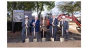 Five people in hardhats holding shovels for a groundbreaking ceremony