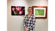 Kelley Krohnert standing in front of photos of flowers, and another of abstract green perspective lines
