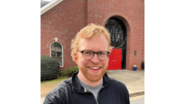 Ben Day standing in front of brick church building smiling