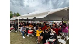 A crowd of people enjoying food under a tent
