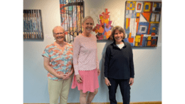 Three women collage artists in front of a gallery display of collage